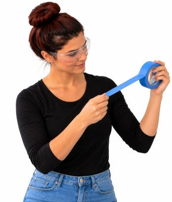 Woman using painters tape, to paint a geometric feature wall