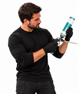 Man holding a foam gun to fit rigid PIR insulation boards to garage walls