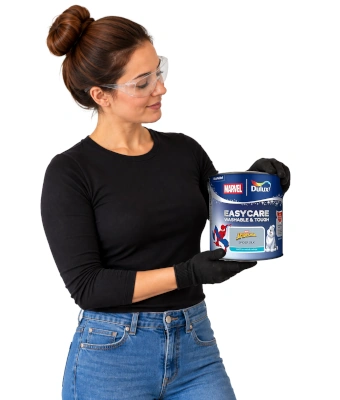 Lady holding a can of paint to paint a spider-man-iinspired skyline feature wall with dulux easycare disney paint